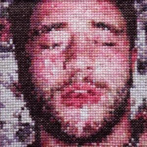 Glazed — original 4×4 inch hand-stitched cross-stitch portrait of a dark-haired man, eyes closed, lips slightly parted, rendered in rose, plum, burgundy, and cream embroidery thread